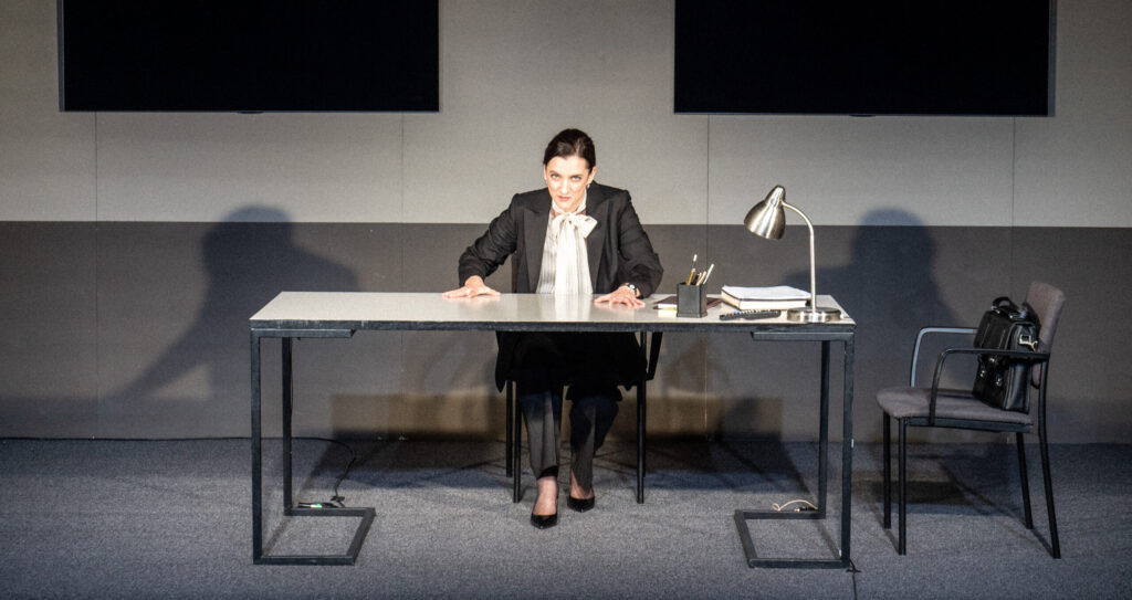 Tessa Jane Ensler (Marian Eplik) kummardumas kavala pilguga oma töölaua taga.