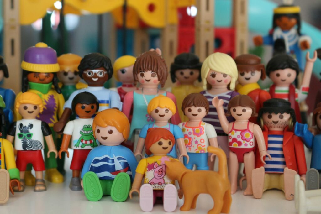 Värviline Playmobili mängufiguriinide kogu – mitmekesised tegelased erinevas riietuses, sealhulgas lapsed ja täiskasvanud, koos oranži kassi kujukesega.`